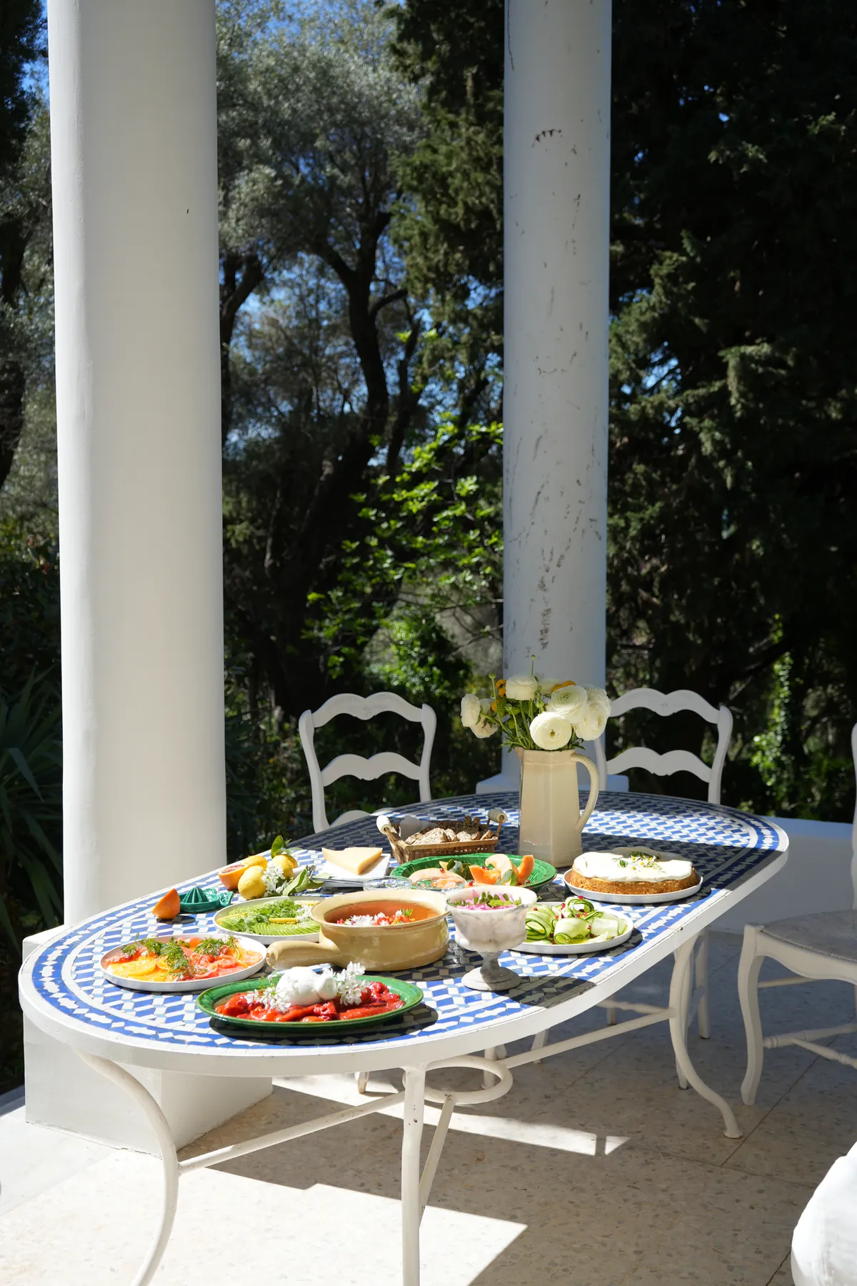 A mosaic table laid on a sunlit terrace
