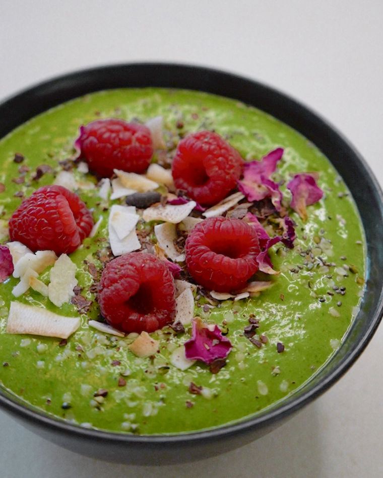 A green smoothie bowl with raspberries